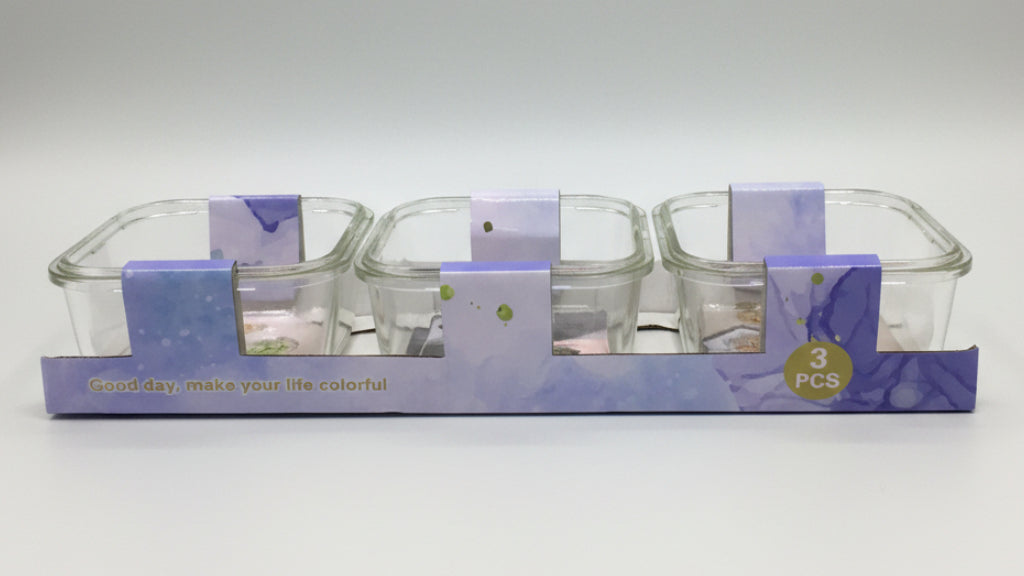 Set of three glass containers with purple lids in packaging on a white background