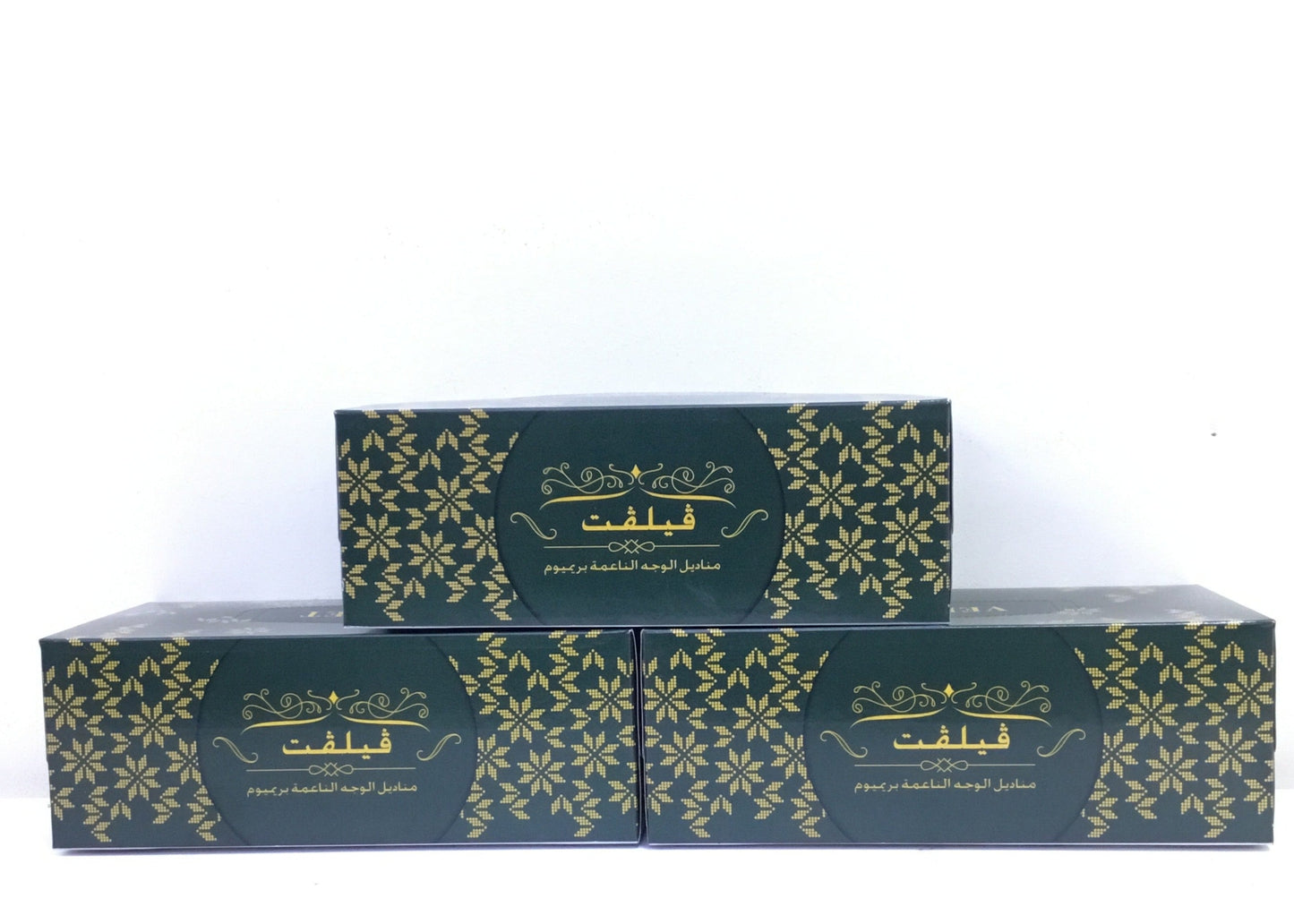 Two green boxes with gold floral patterns on a white background
